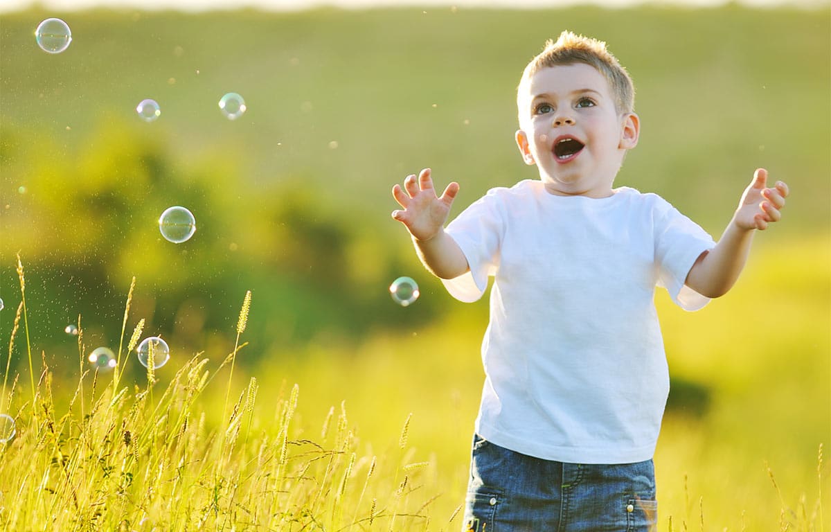 A young boy running happily through a field